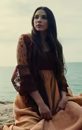 a woman sitting on a rock near the water