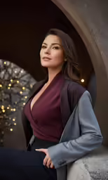 a woman in a purple jacket leaning on a column