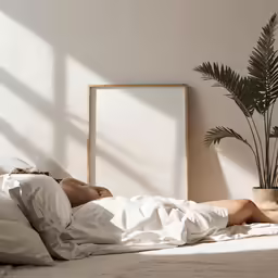 woman laying on bed in white bedroom with plant