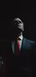 a man with a red tie is looking at something
