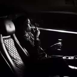 a woman sitting in a car smoking and drinking a beverage