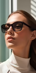 a woman wearing glasses looks off into the distance