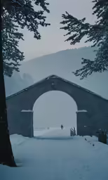 snow covered ground and rocks with large archway in middle of the walkway
