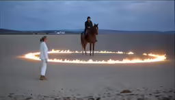 two people in the middle of a beach on fire