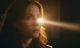 a beautiful woman standing next to an industrial light