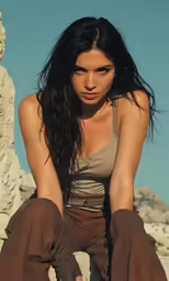a young woman sitting on a rock posing for the camera