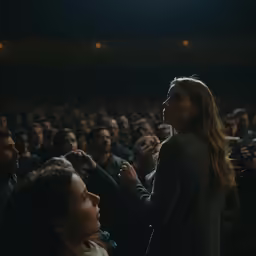 a woman standing in front of a crowd next to an audience