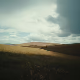 a beautiful field that is mostly empty under clouds