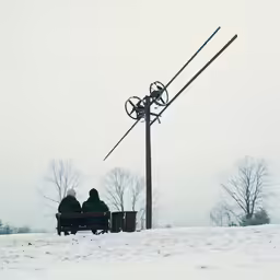two people sit on a bench while looking at the sky