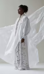 a woman with white clothing standing in a studio