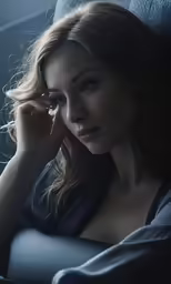 woman sitting in car holding her hand to her ear