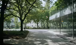 a glassy building is sitting next to a tree filled street