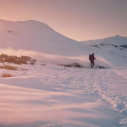 a person walking through a snowy field towards a mountain