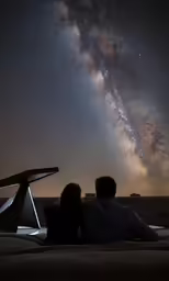 a man and woman are looking at the stars and milky
