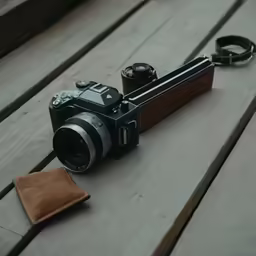 a camera and a leather purse sitting on a wooden bench