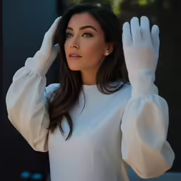 a woman in a white blouse posing with her hands up
