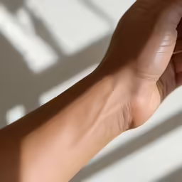 the arm of an adult holding onto an apple in the sun