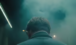 a man looking out at a smoke filled night