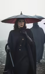 a woman wearing black holding an umbrella and a purse in her hand