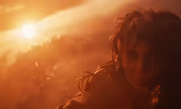 a girl with flowing hair in front of an orange sunset