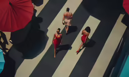 two women are walking down a paved walkway with red umbrellas