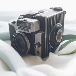 an old camera on top of a bed next to flowers