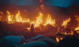 large orange flames spread over trash and rubble