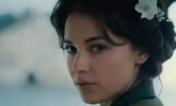 a woman is dressed for a special event and looking into the distance