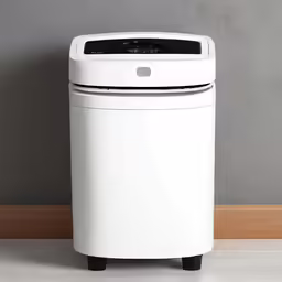 a white electronic trash can with a grey wall