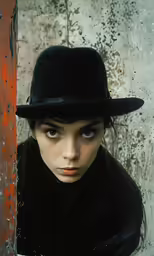 a woman wearing a hat and standing with her hands in her pockets