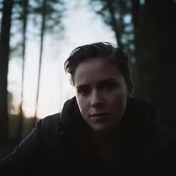 a person posing in a forest at sunset
