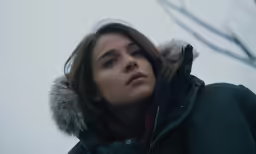 woman in a coat stares intently at something