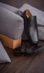 a pair of black shoes are next to a gray couch
