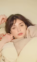 a girl sitting in bed while holding her head and looking down