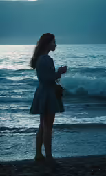 a woman standing on the beach in a dress