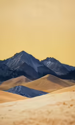 a large sandy dune area is surrounded by mountains