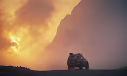 the car is driving on the dirt road