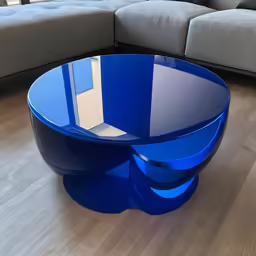 a round blue glass coffee table sitting on top of a wooden floor