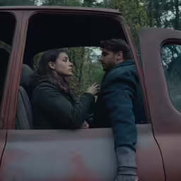 the man and woman stand next to each other in a red truck