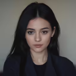 a woman with long hair wearing a black shirt and black blazer