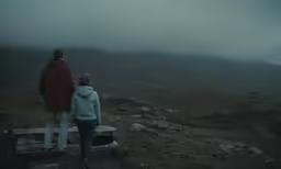 a man and woman standing on top of a wooden bench