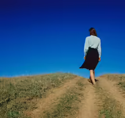 a woman walking up a dirt road