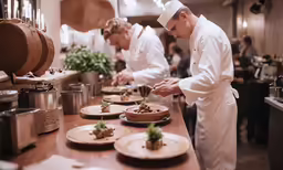 two men in chefs uniform work together at an industrial counter