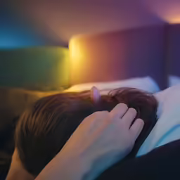 a person sleeping on a bed, the hands on the head of the bed