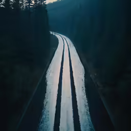 a view of a snow covered road next to a forest