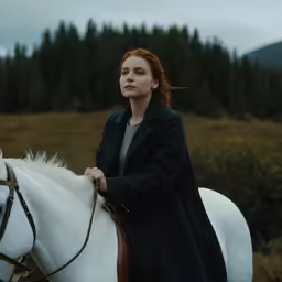 a woman is riding a horse in the country