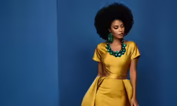 a woman wearing a yellow dress poses against a blue background