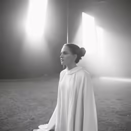 a woman in a white robe standing in the dark