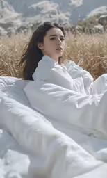 a woman lying on top of a white sheet in the snow
