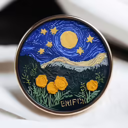 a brooch that says enjoy in front of mountains and stars